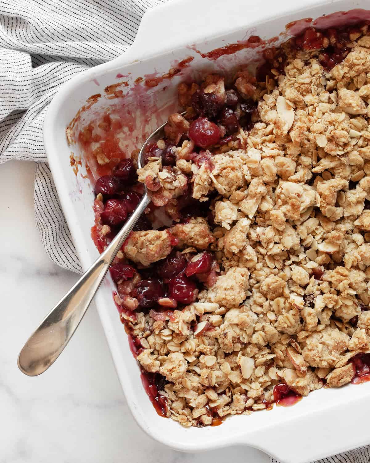 Portion spooned out of cherry crumble in baking dish.