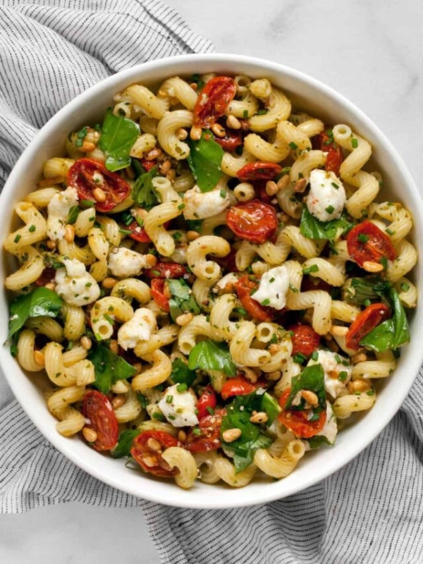 Pesto pasta salad with roasted tomatoes and mozzarella in a bowl.