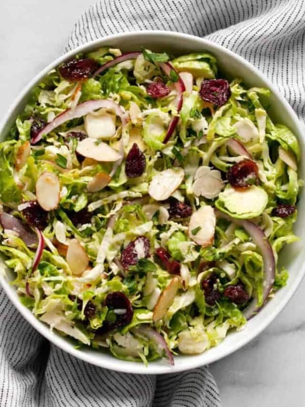 Shredded brussels sprout salad with cranberries. almonds and parmesan in a small bowl.