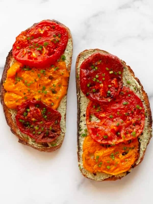 Two slices of toast with roasted tomatoes and pesto cheese spread.