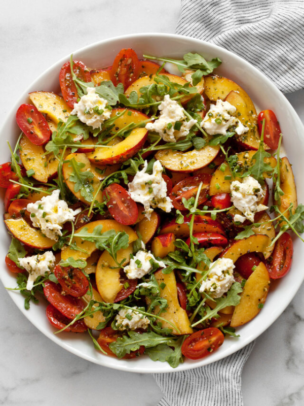 Tomato peach burrata salad on a plate.