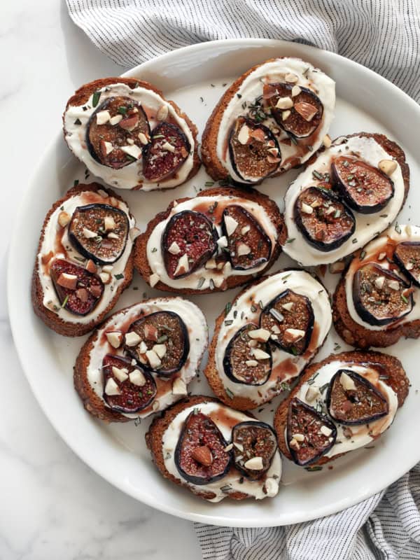 Toasts with whipped goat cheese and roasted figs on a plate.