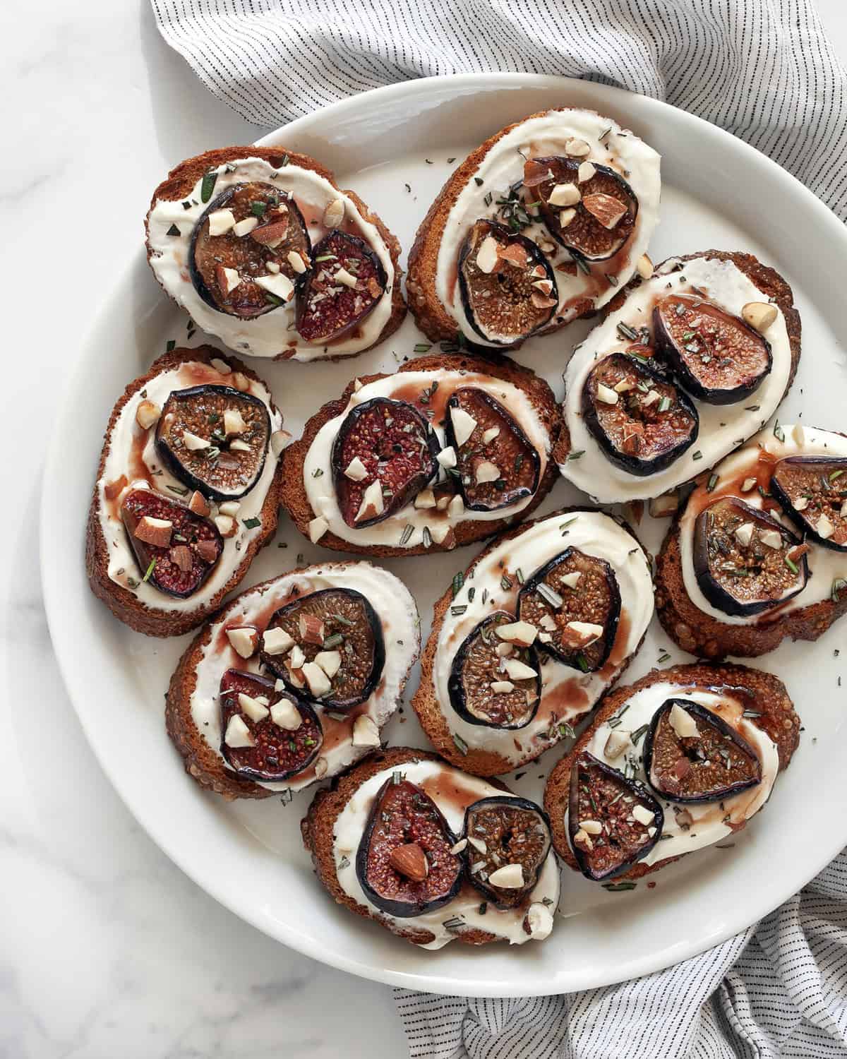 Toasts with whipped goat cheese and roasted figs on a plate.