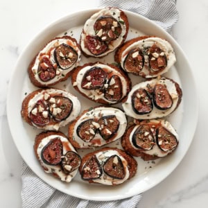 Toasts with whipped goat cheese and roasted figs on a plate.