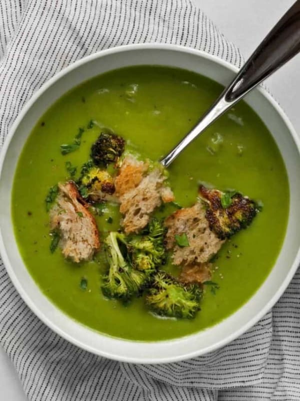 Broccoli soup topped with roasted broccoli and croutons in a bowl.