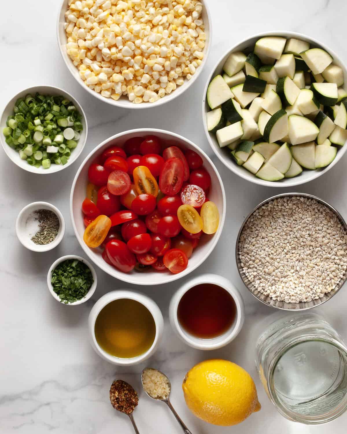 Ingredients including barley, tomatoes, corn, zucchini, olive oil, red wine vinegar, lemon, garlic, oregano, parsley, mustard, salt and pepper.