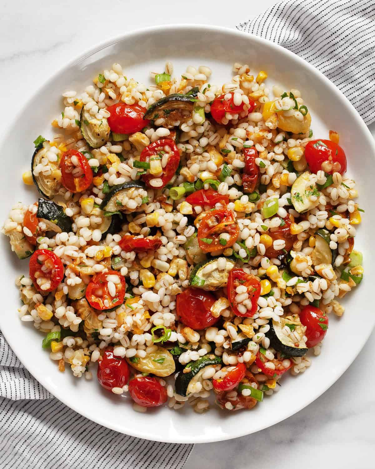 Tomato, corn & zucchini barley salad in a bowl.