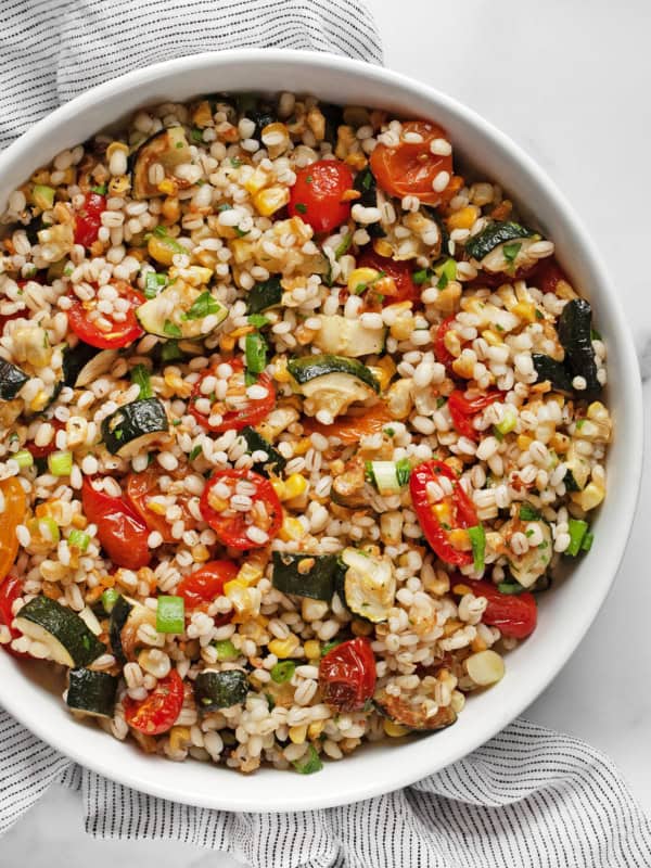 Barley salad with roasted tomatoes, corn & zucchini in a bowl.