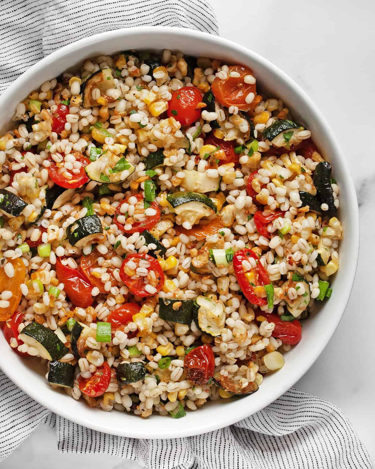 Barley salad with roasted tomatoes, corn & zucchini in a bowl.