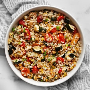 Tomato, corn & zucchini barley salad in a bowl.