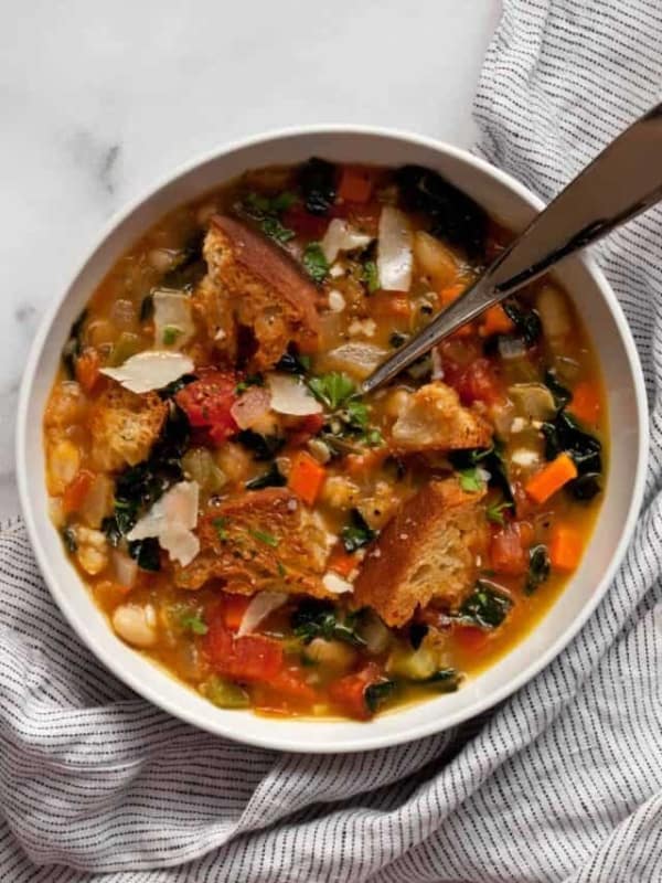 One bowl of Tuscan white bean soup garnished with Parmesan cheese.