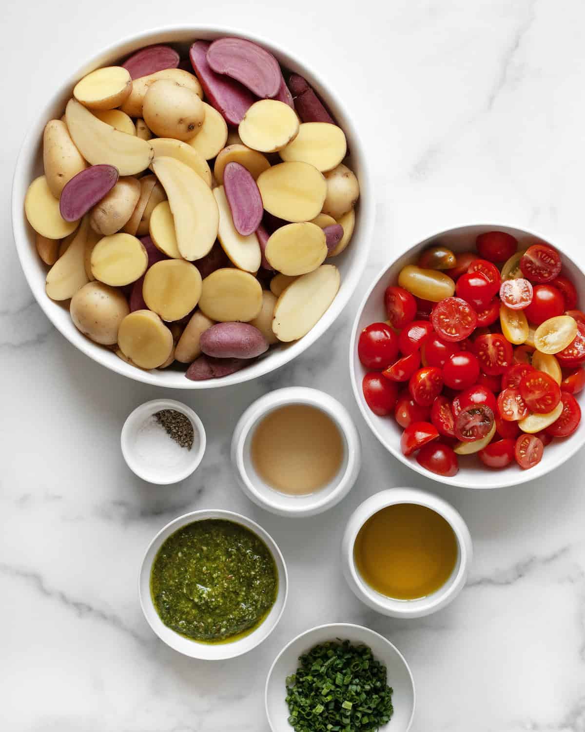 Ingredients including potatoes, tomatoes, pesto, vinegar, chives, olive oil, salt & pepper.