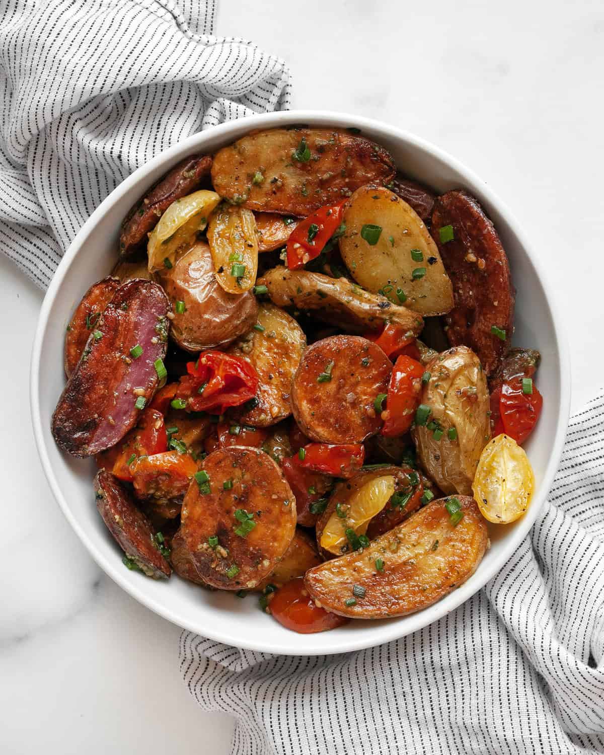 Pesto potato salad with tomatoes in a small bowl.