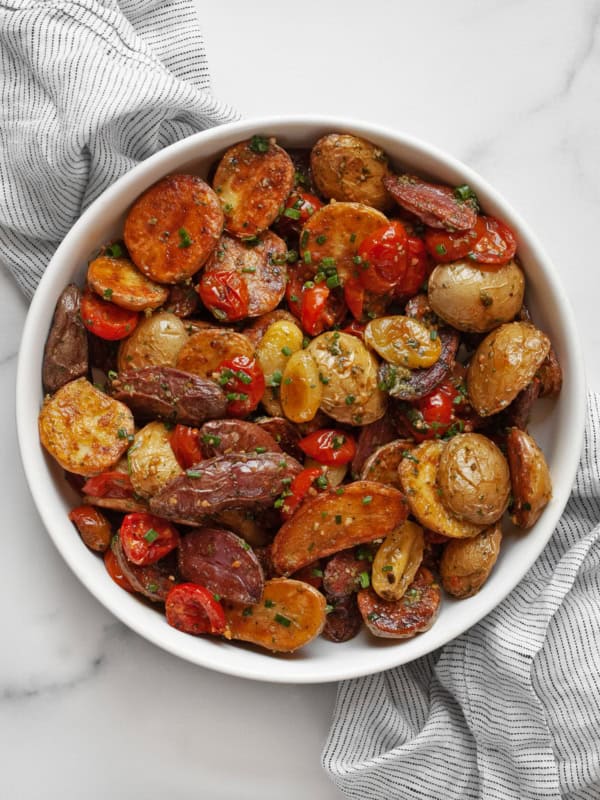 Roasted potato salad with tomatoes and pesto vinaigrette in a large bowl.