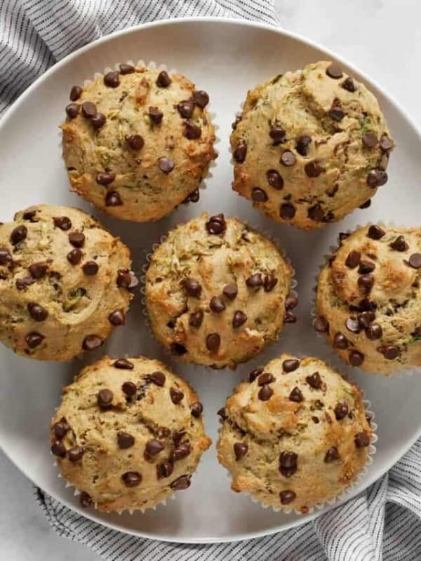 Seven chocolate chip zucchini muffins on a plate.