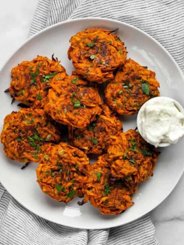 Baked sweet potato fritters on a plate with Greek yogurt.