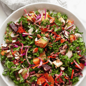 Roasted beet and orange kale salad on a plate.