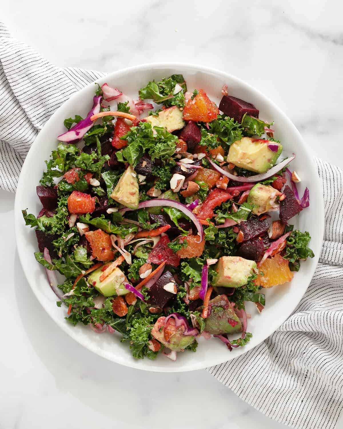 Roasted beet and orange kale salad on a plate.