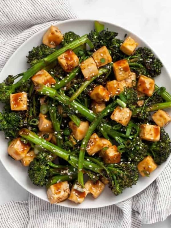 Baked tofu and broccolini with teriyaki sauce on plate.