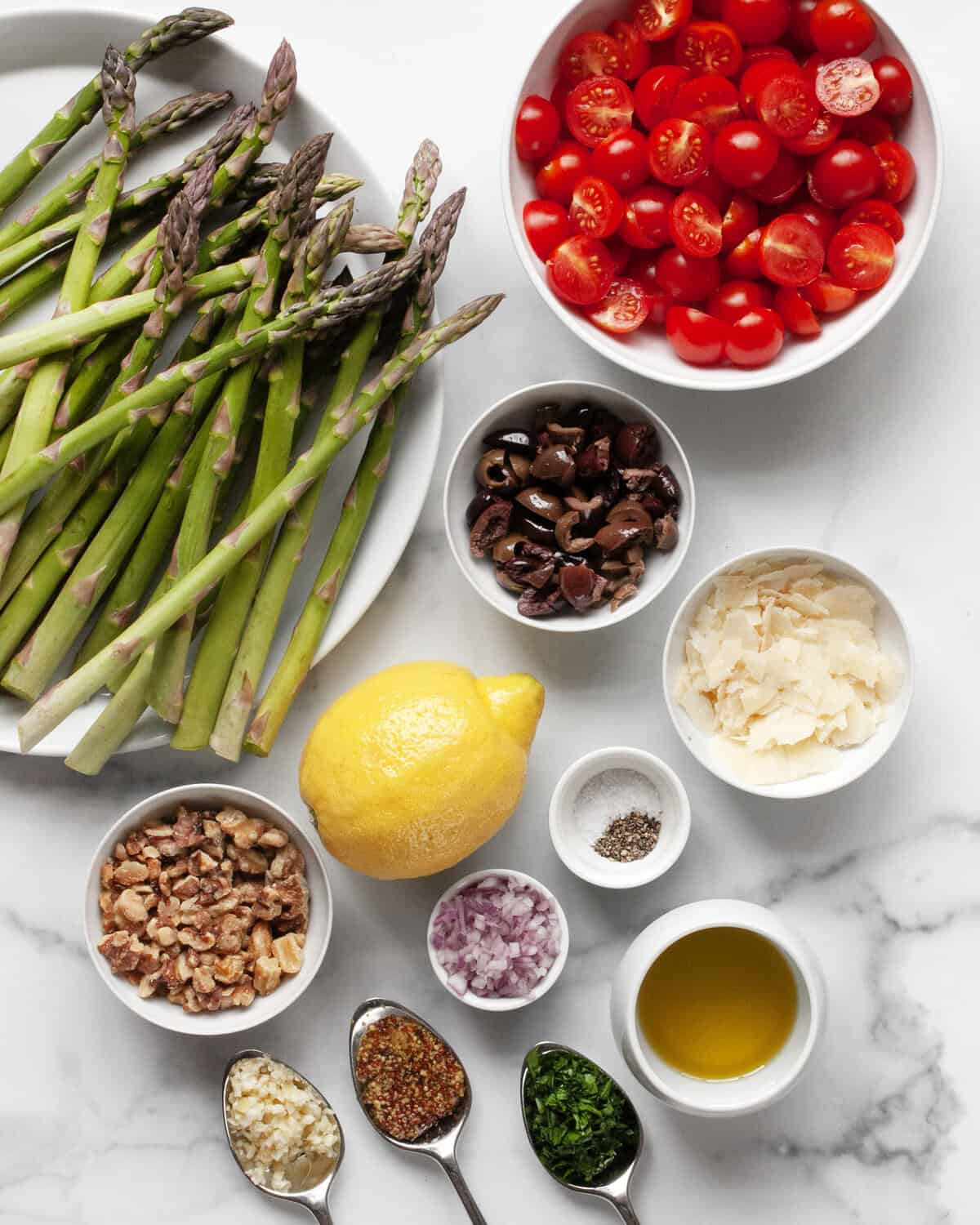 Ingredients including asparagus, tomatoes, olives, walnuts, parmesan, parsley, garlic, mustard, olive oil and lemon.