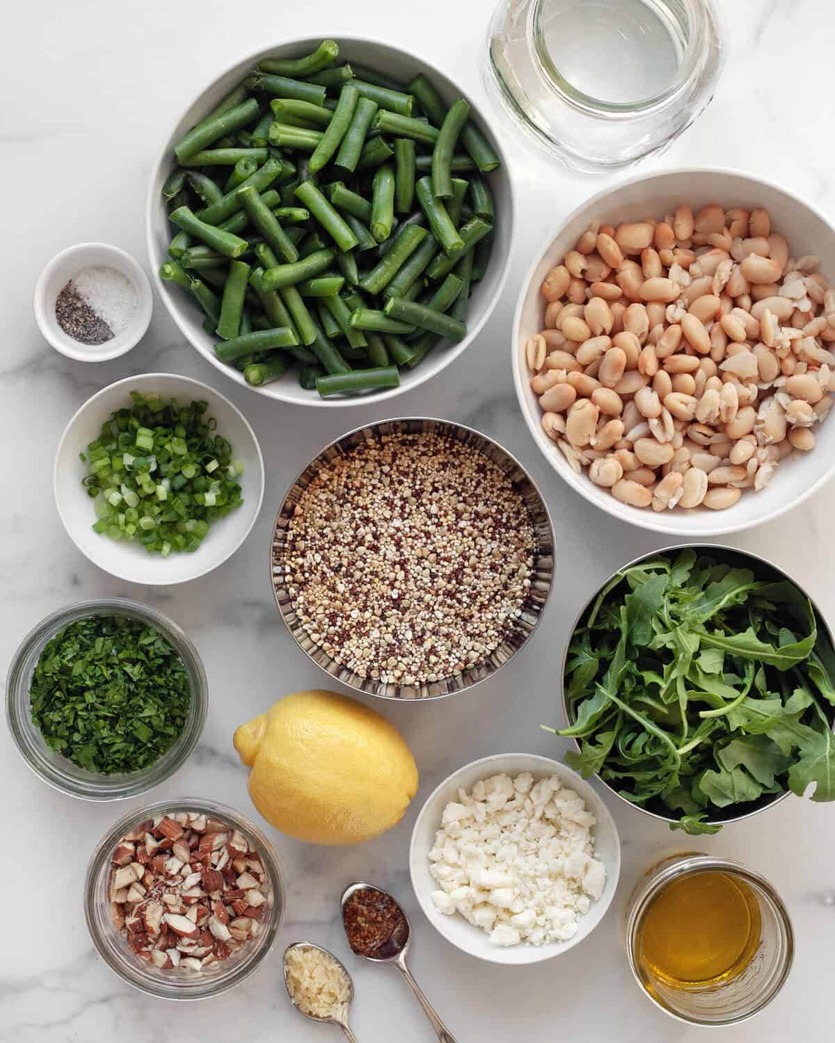 Ingredients including green beans, white beans, quinoa, lemon, almonds, feta, olive oil, arugula, scallions, salt and pepper.