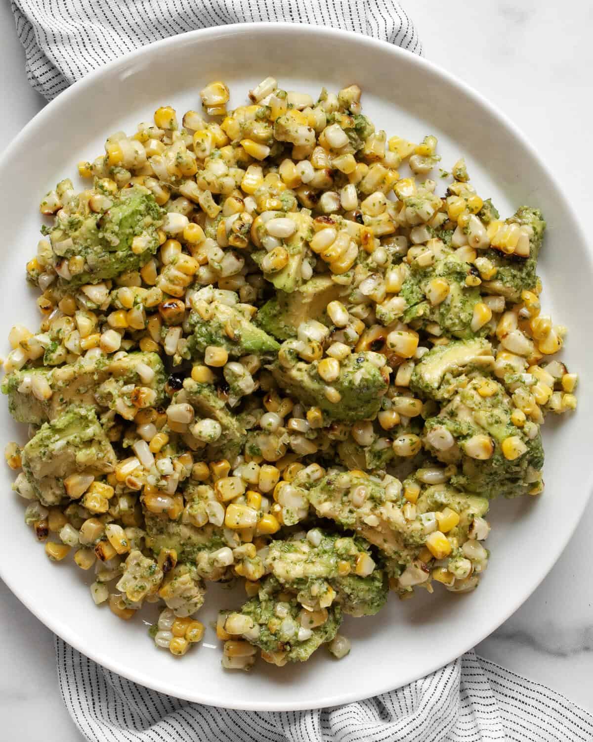 Grilled corn and avocados with cilantro pesto on a plate.