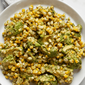 Grilled corn and avocados with cilantro pesto on a plate.