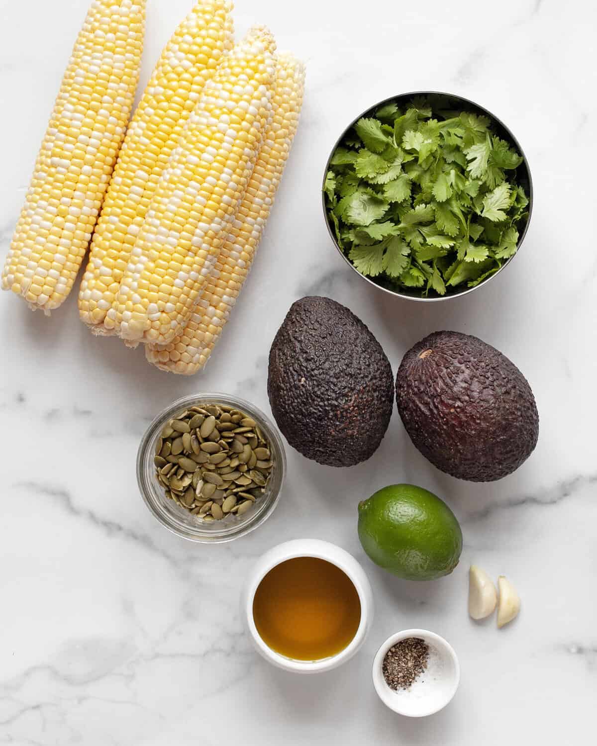 Ingredients including corn, avocados, cilantro, pumpkin seeds, garlic, lime, olive oil, salt & pepper