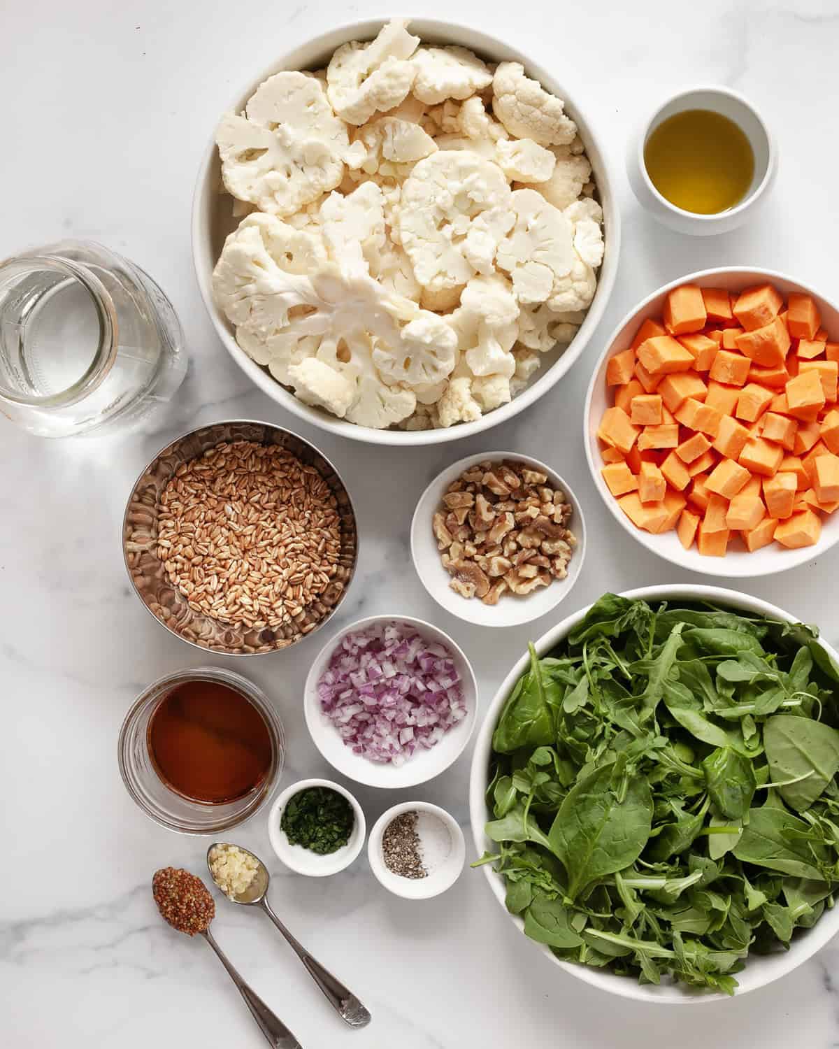 Ingredients including sweet potatoes, cauliflower, baby arugula & spinach, red onions, walnuts, sherry vinegar, olive oil, mustard, garlic, salt and pepper.