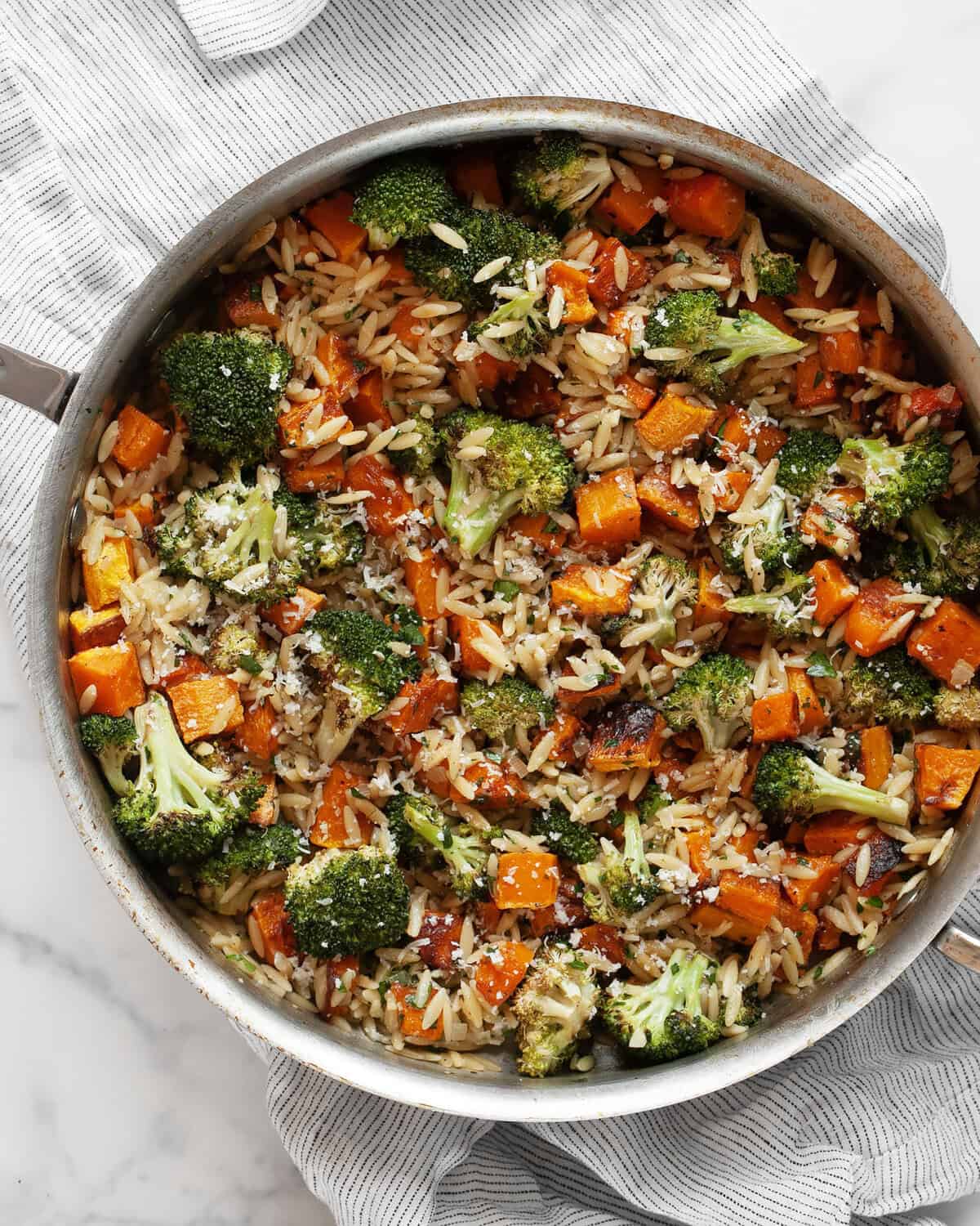 Roasted vegetable orzo with butternut quash and broccoli in a skillet. 