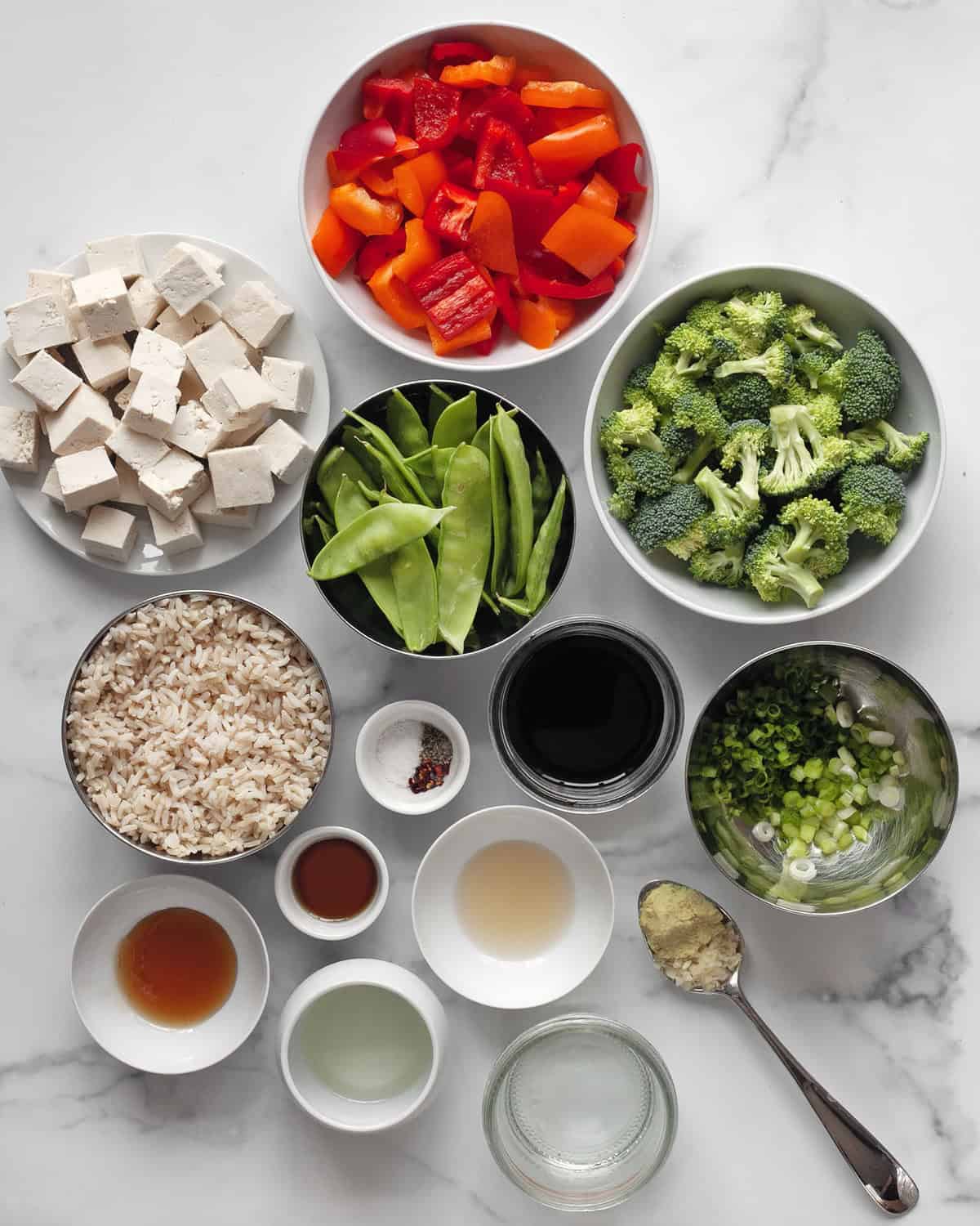 Ingredients including rice, peppers, snow peas, broccoli, tofu, soy sauce, garlic, ginger and oil.