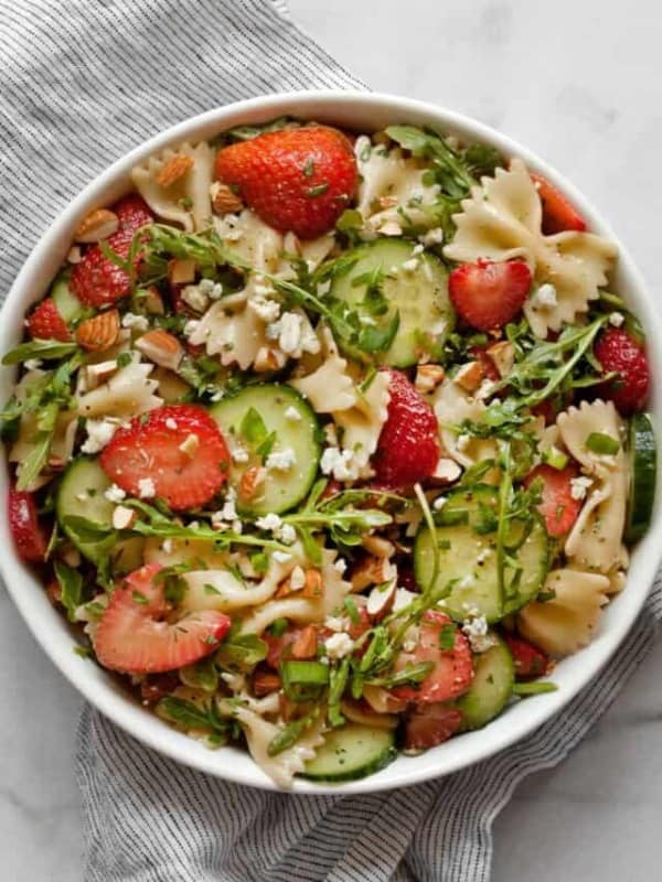 Pasta salad with cucumbers and strawberries in a bowl.