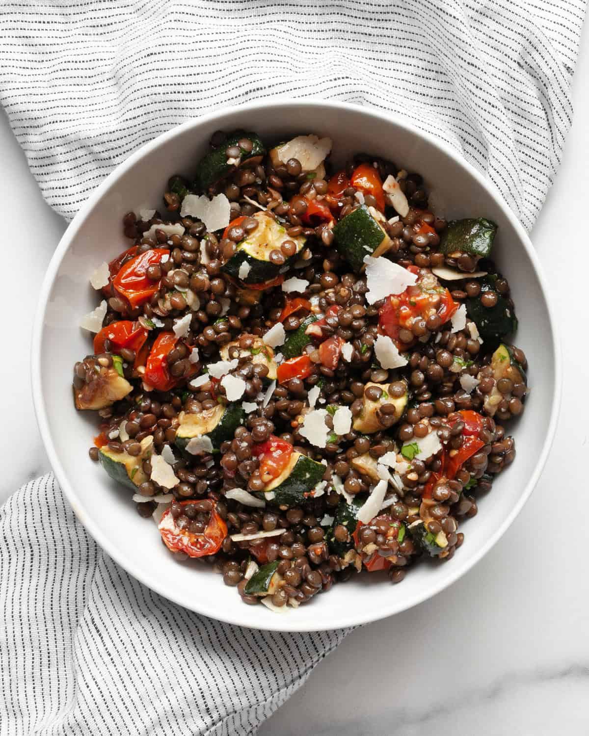 Lentil salad with roasted zucchini and tomatoes in a bowl.