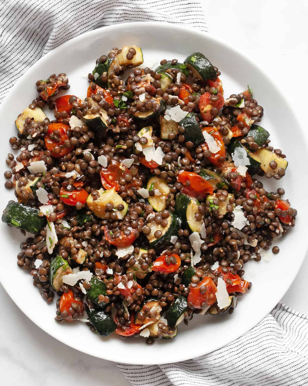 Roasted tomato zucchini lentil salad on a plate.