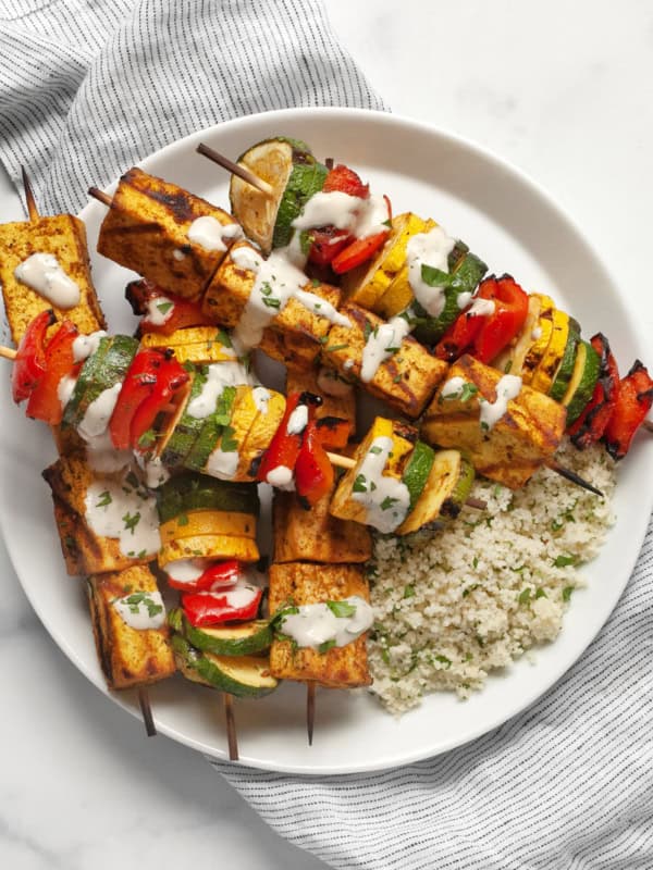 Grilled tofu and vegetable skewers with couscous on a plate.