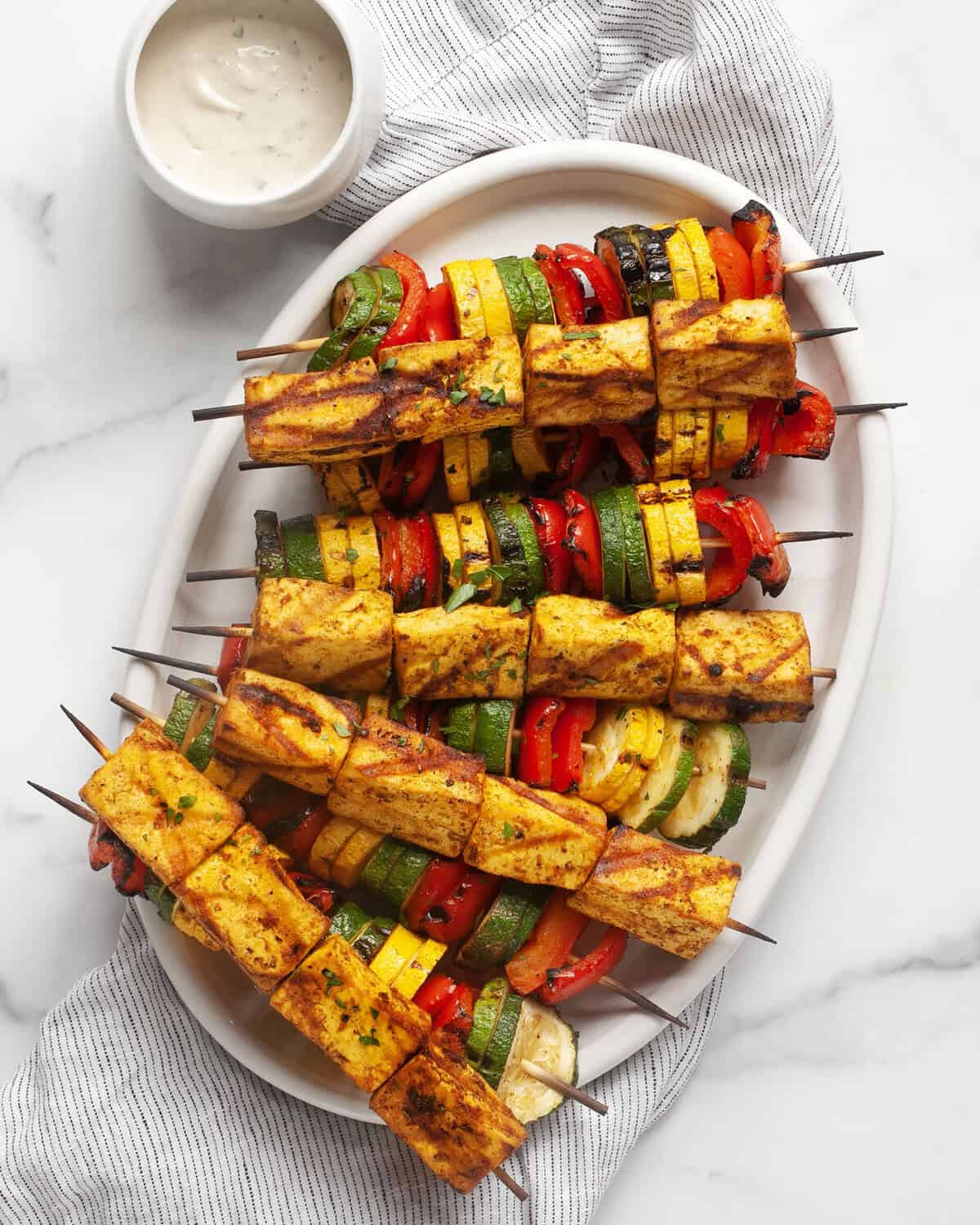 Grilled tofu and vegetable skewers on a serving platter.