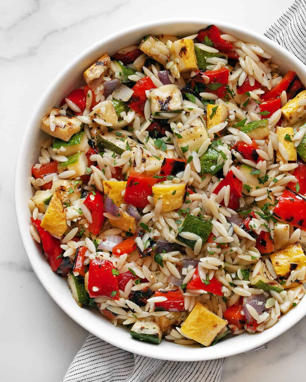 Grilled vegetable orzo pasta salad in a bowl.