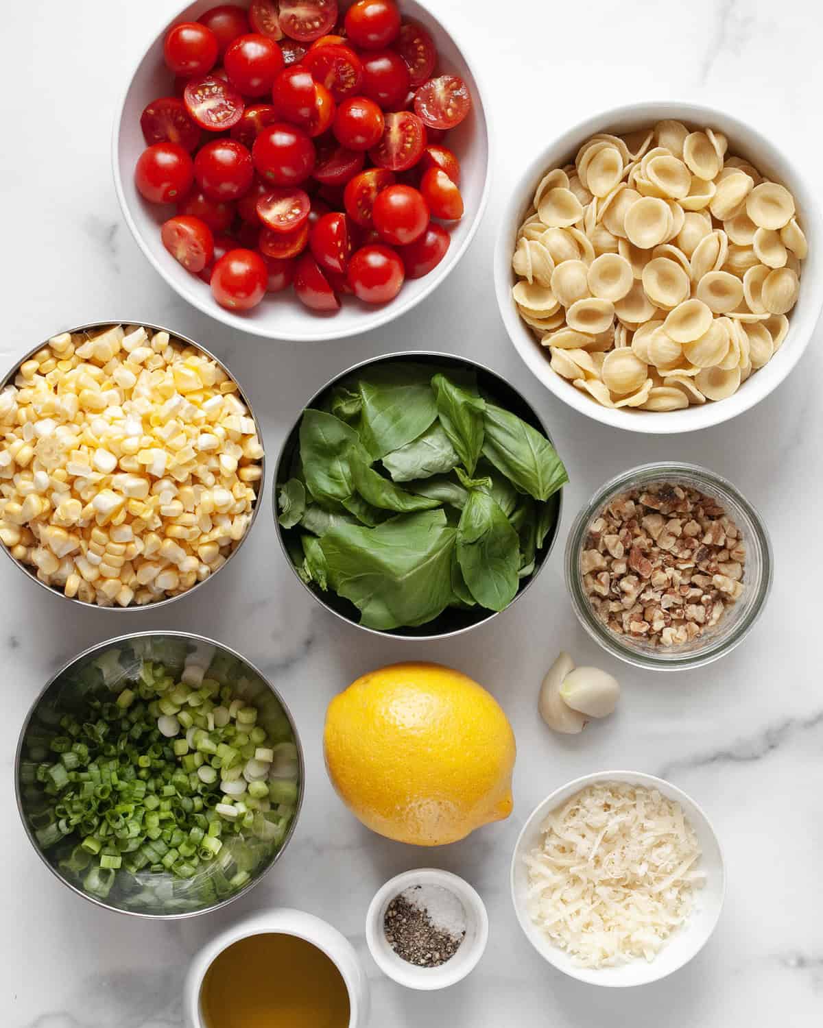 Ingredients including tomatoes, corn, pasta, basil, parmesan, garlic, lemon, olive oil, scallions, salt and pepper.