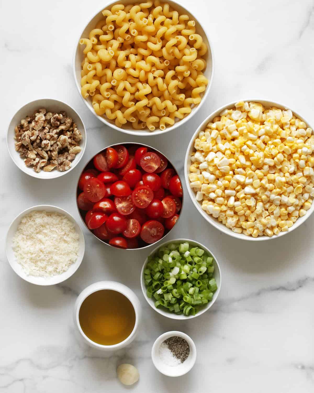 Ingredients including corn, tomatoes, walnuts, scallions, olive oil, parmesan, cavatappi, salt and pepper.