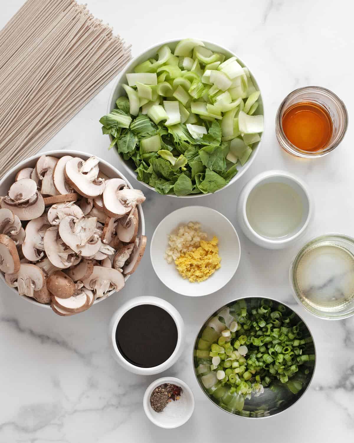 Ingredients including bok choy, mushrooms, soba noodles, scallions, garlic, ginger and spices.