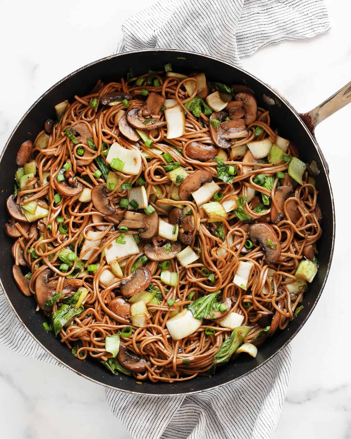 Mushroom and bok choy soba noodle stir-fry in a skillet.