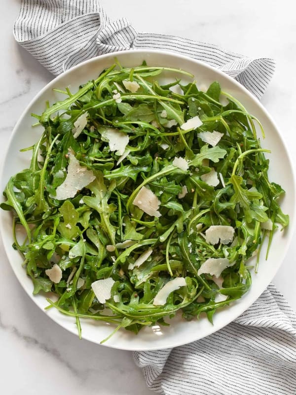 Arugula salad with lemon vinaigrette on a plate.