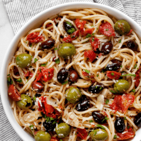 Spaghetti with tomatoes, olives & artichokes on a plate.