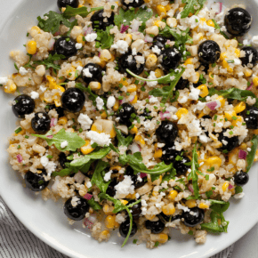 Blueberry salad with grilled corn, quinoa and arugula on a plate.