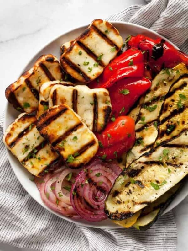 Grilled halloumi cheese with grill marks and grilled zucchini, squash, pepeprs and onions.