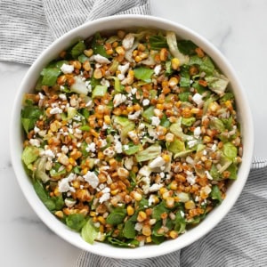 Chopped salad with roasted corn, romaine, feta and scallions in a bowl.
