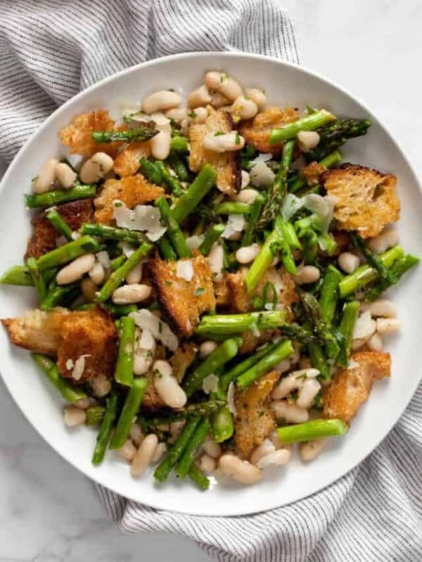 Asparagus salad with cannellini beans and croutons on a plate.