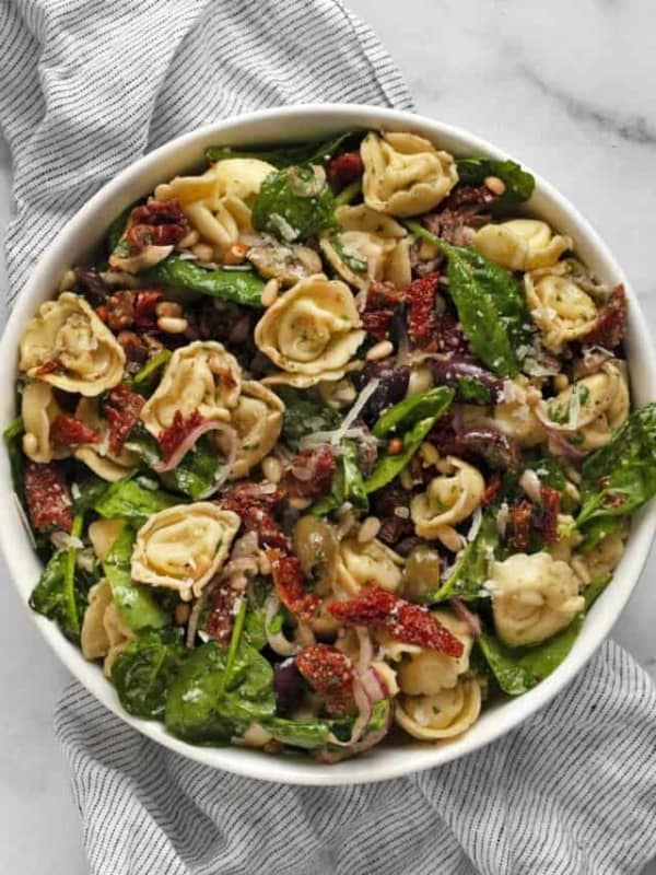 Pasta salad with tortellini, sun dried tomatoes, olives and spinach.