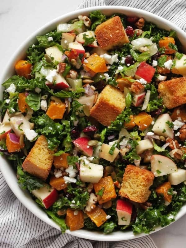 Salad with roasted butternut squash, apples, kale and romaine in a bowl.