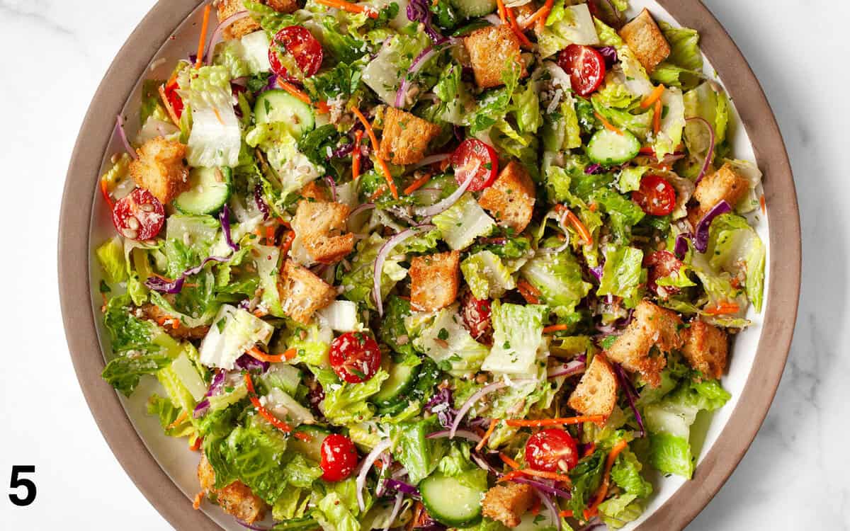 Salad tossed with vinaigrette in a bowl.